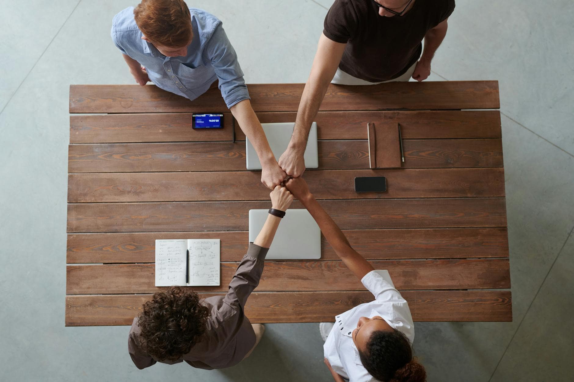 Group fist bump at a meeting table, illustrating Pathfinder’s commitment to inclusive, nationwide conflict resolution.